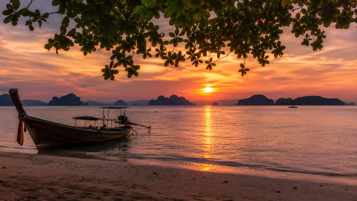 Atardecer en la playa de Krabi con barcos longtail en el mar de Andamán