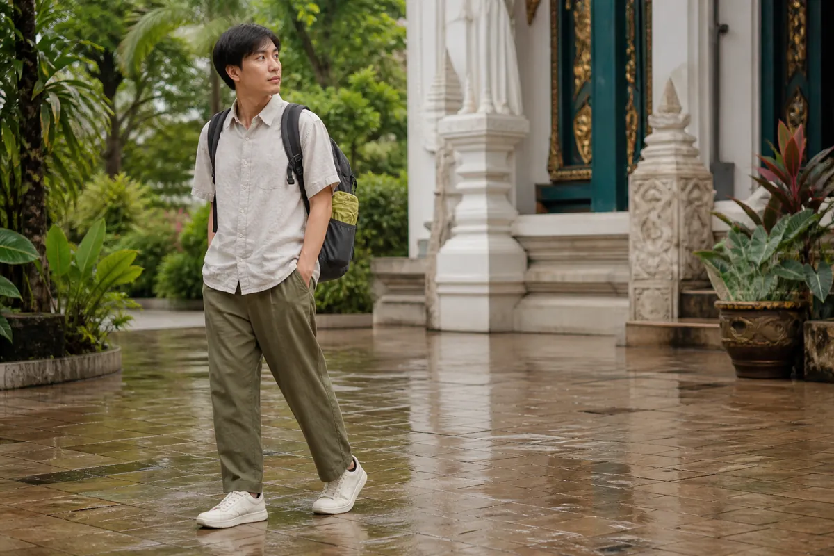Viajero con ropa ligera que cubre hombros y rodillas junto a un templo después de llover